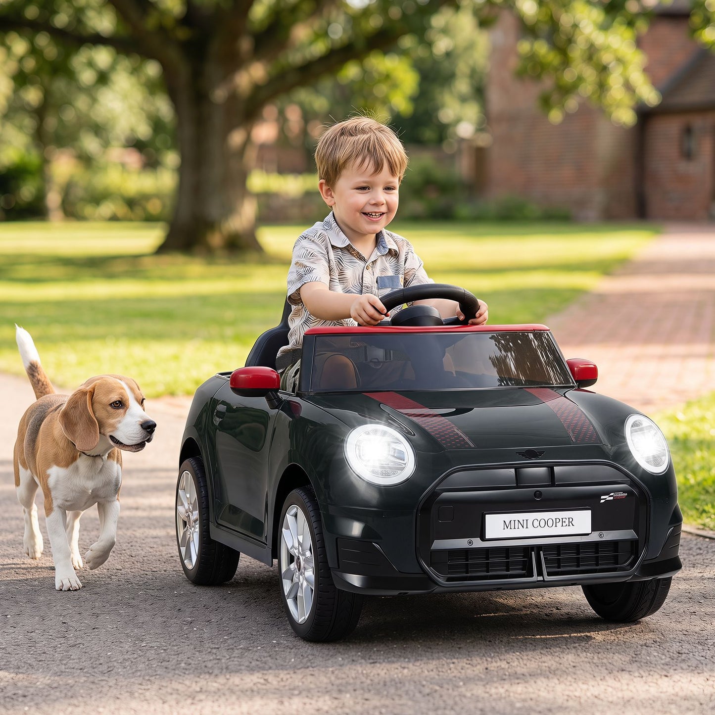 Vaikas važiuoja juodu Mini Cooper stiliaus elektriniu automobiliu lauke