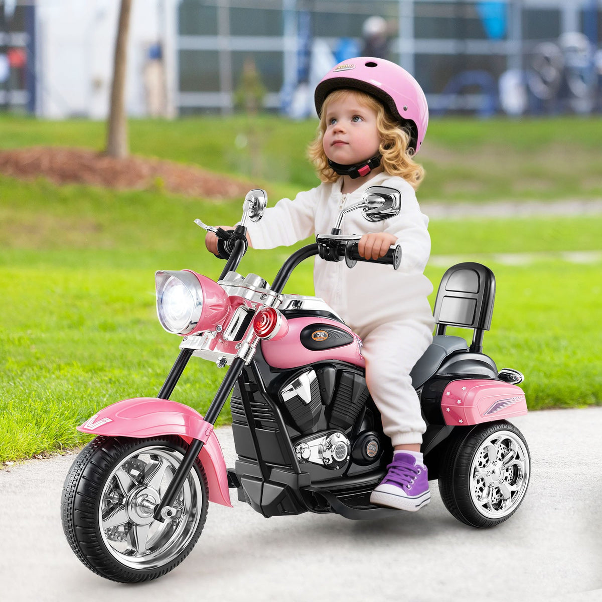 Vaikas važiuoja rožiniu elektriniu triračiu motociklu lauke